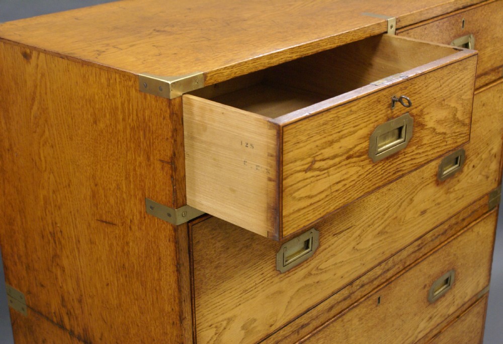 A two-part oak military campaign chest featuring two short over three long drawers, flush brass handles, protective brass corners, and turned feet. View VI