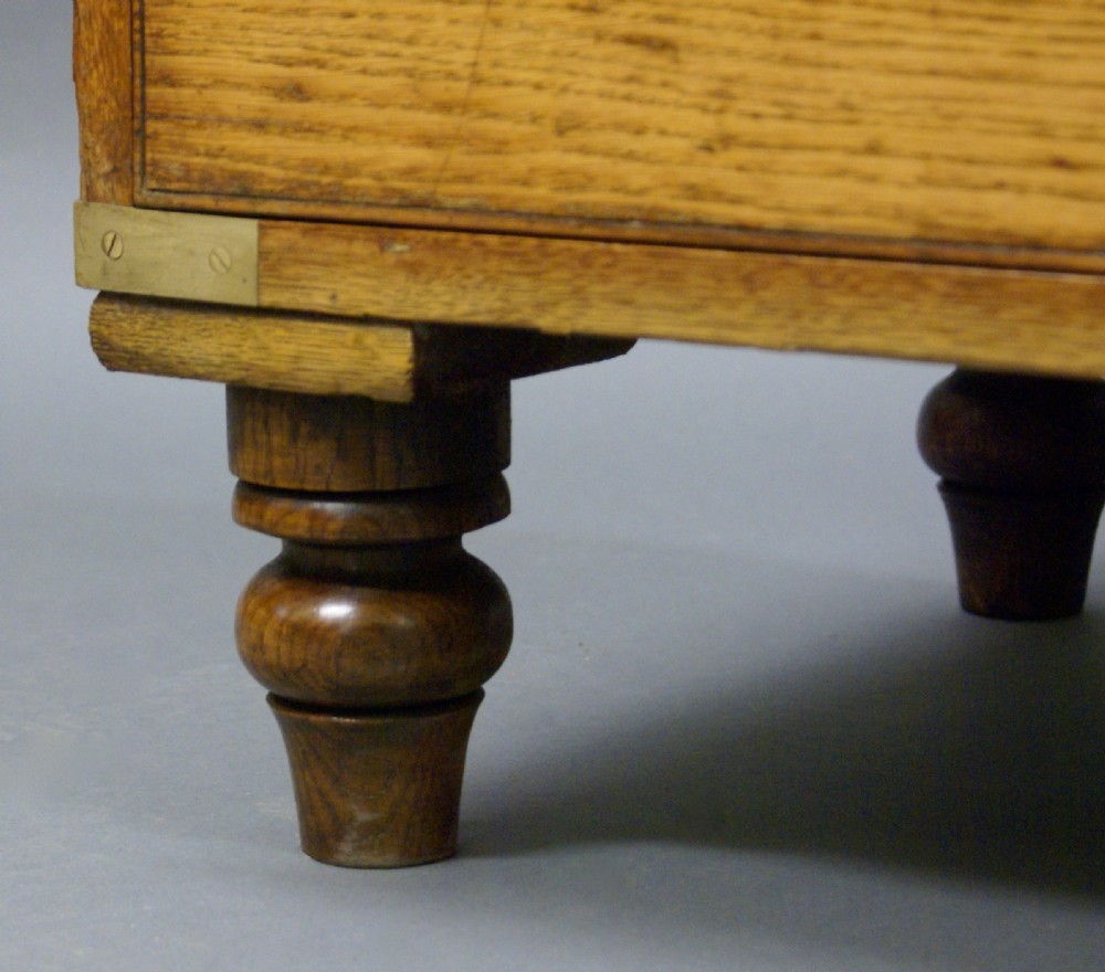 A two-part oak military campaign chest featuring two short over three long drawers, flush brass handles, protective brass corners, and turned feet. View VII