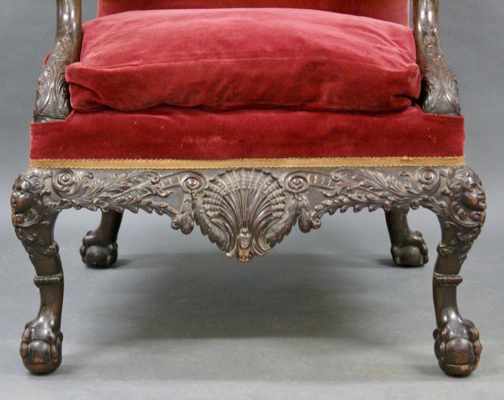 A Georgian style carved mahogany library armchair upholstered in red velvet with eagle head armrests and ball-and-claw feet. View VI