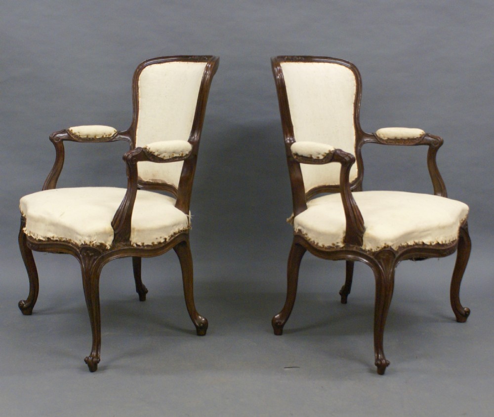A pair of carved dark wood French Hepplewhite armchairs featuring cartouche backrests, padded armrests, and neutral cream fabric upholstery. View II