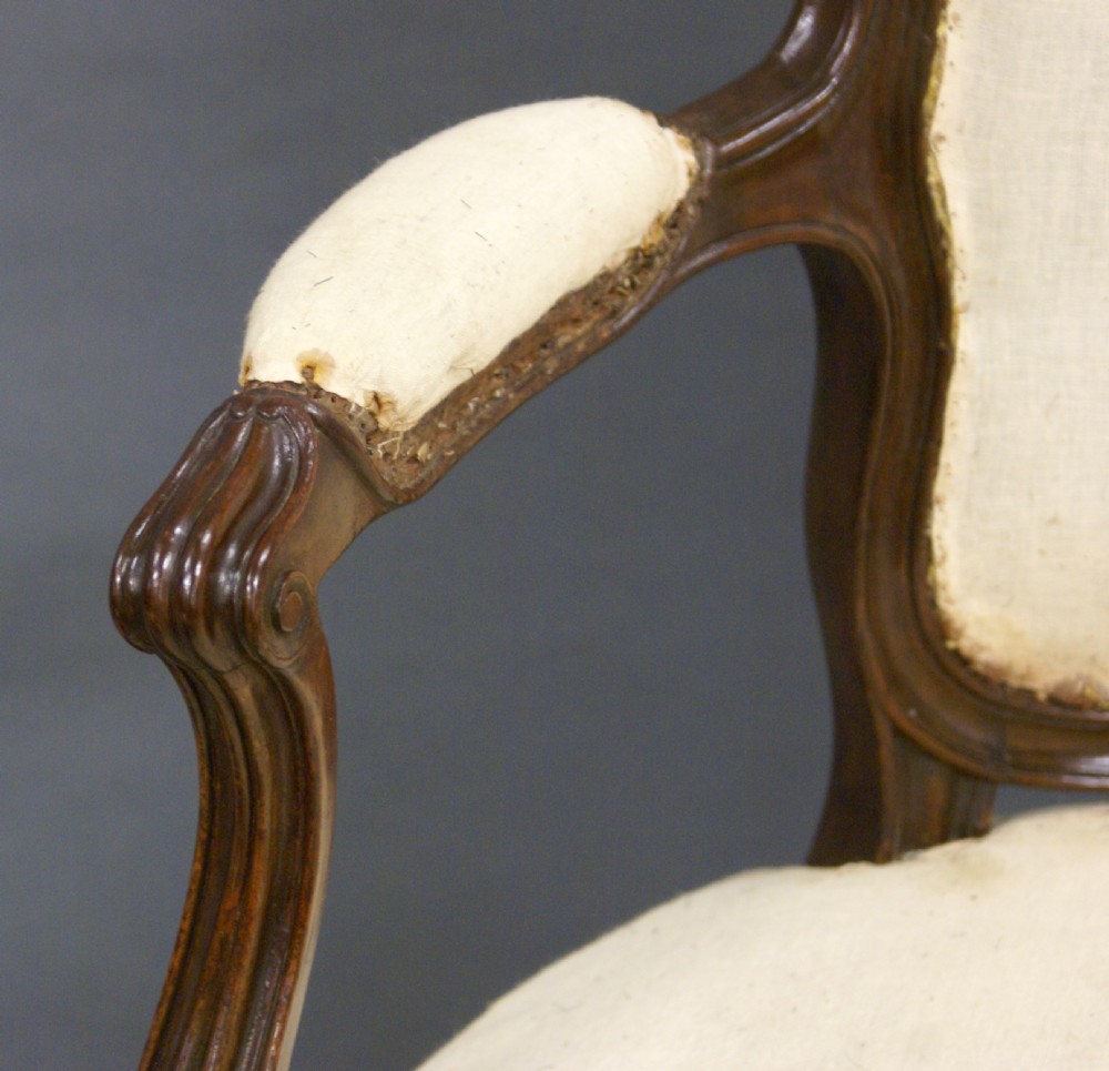 A pair of carved dark wood French Hepplewhite armchairs featuring cartouche backrests, padded armrests, and neutral cream fabric upholstery. View IV