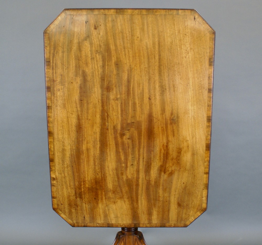 A Regency mahogany tilt-top table positioned upright on a turned tripod pedestal base with brass castors. View III