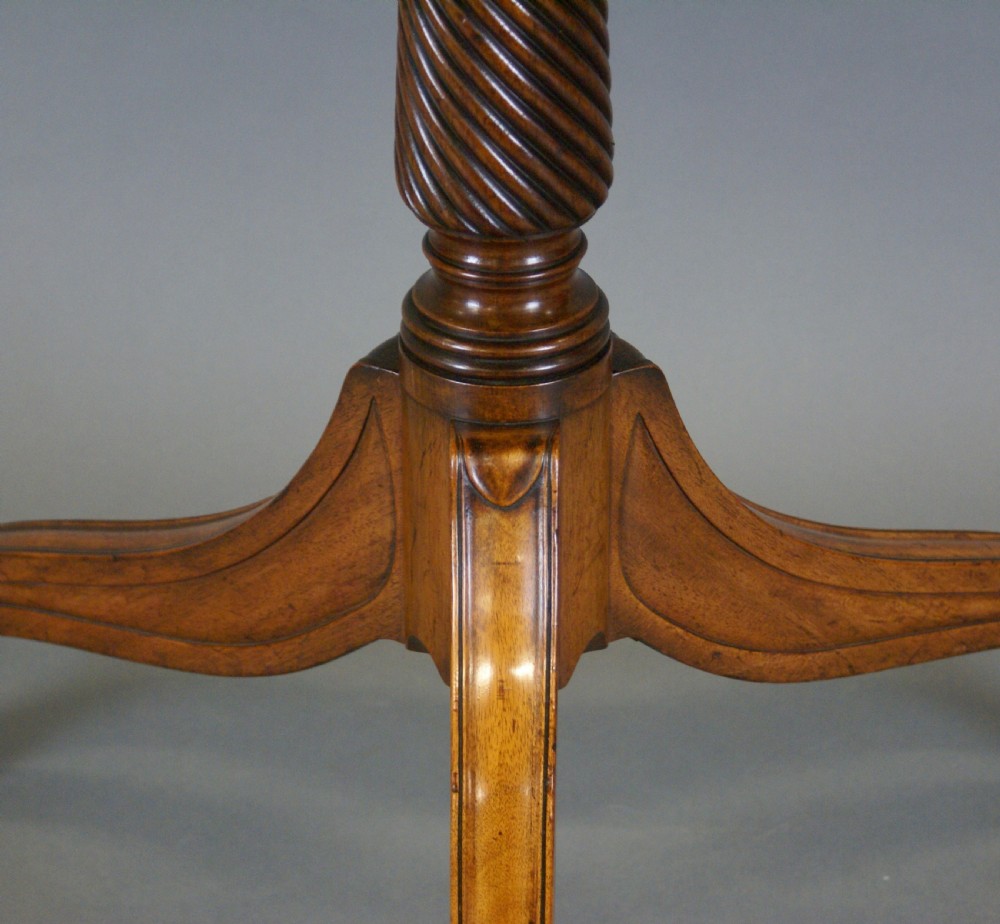 A Regency mahogany tilt-top table positioned upright on a turned tripod pedestal base with brass castors. View VII