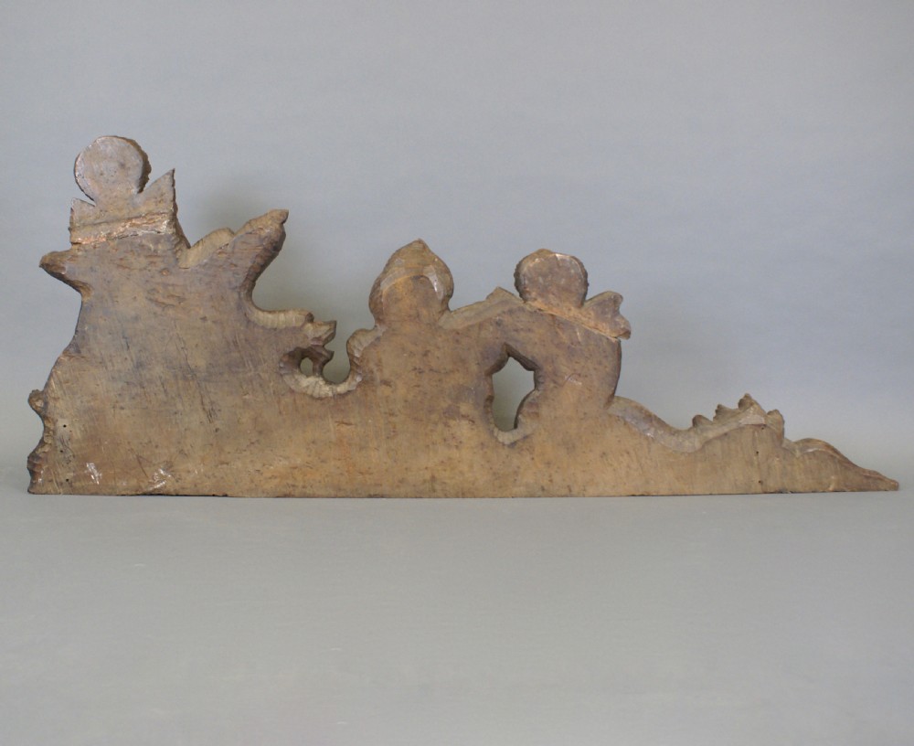A 17th-century carved walnut architectural relief featuring two sculpted putti figures, a central cartouche shield, and a winged mythical beast. View VI