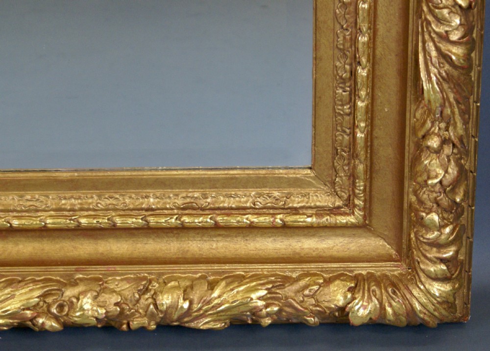 A large rectangular wall mirror featuring an ornate golden giltwood frame with detailed leaf carvings and bevelled glass. View IV