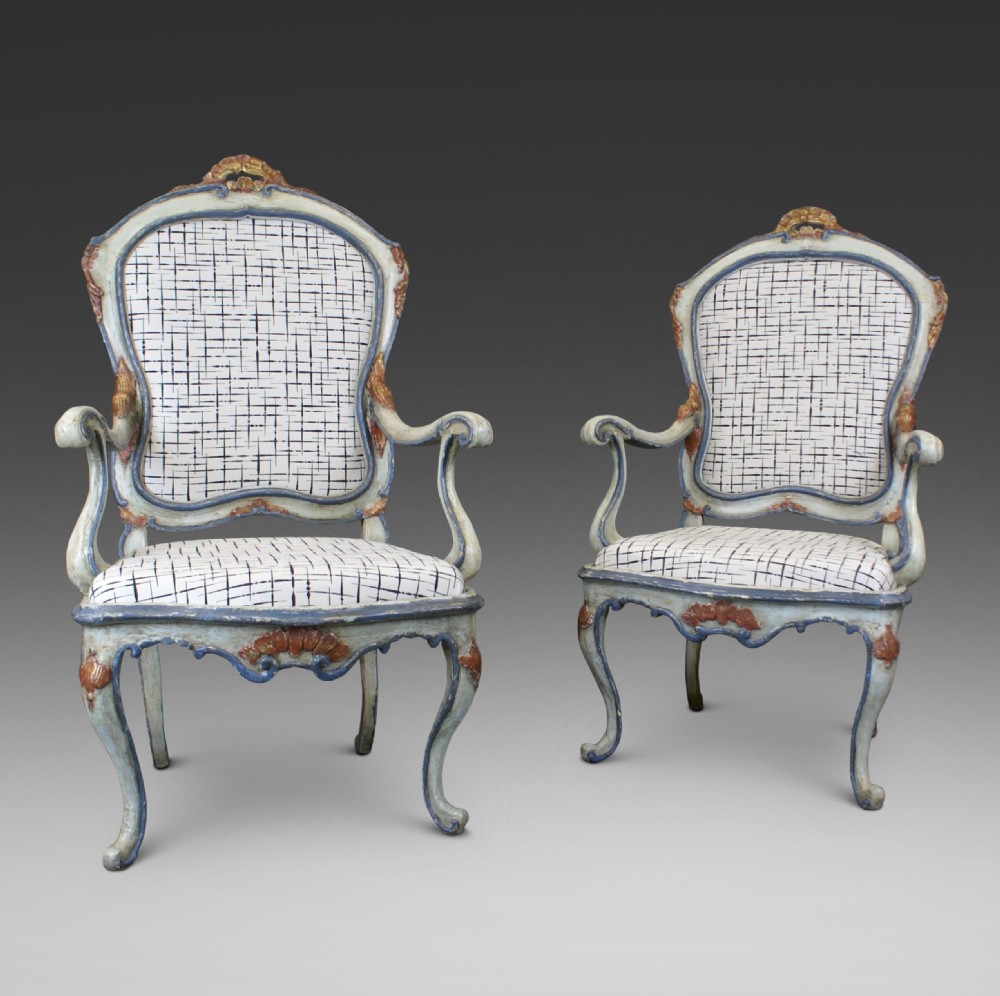 A pair of 18th-century Italian Barocchetto armchairs with pale blue carved wooden frames, red accents, and patterned fabric upholstery.