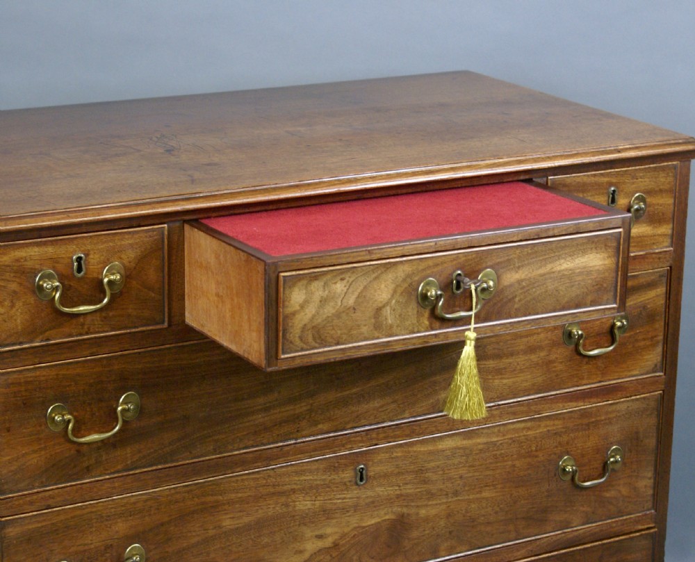 A Georgian mahogany chest of drawers featuring three small top drawers over three long graduating drawers with brass swan-neck handles and bracket feet. View V
