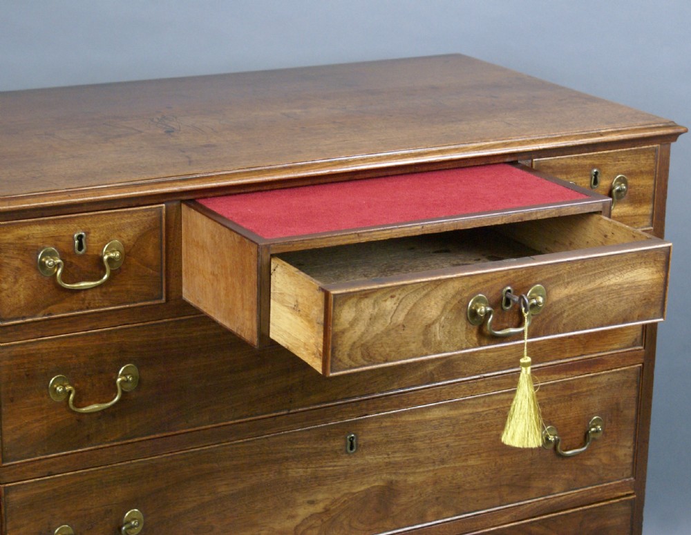 A Georgian mahogany chest of drawers featuring three small top drawers over three long graduating drawers with brass swan-neck handles and bracket feet. View VI