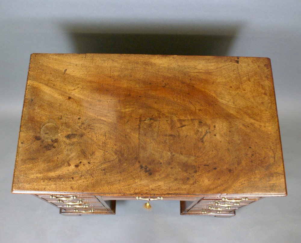 A Georgian mahogany kneehole desk featuring a top drawer over six side drawers, brass swan-neck drop handles, and bracket feet. View III