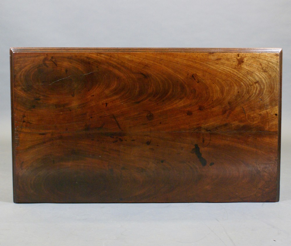 A Georgian Cuban mahogany kneehole desk featuring a long top drawer over six side drawers, a central recessed cupboard, and brass handles on bracket feet. View VI
