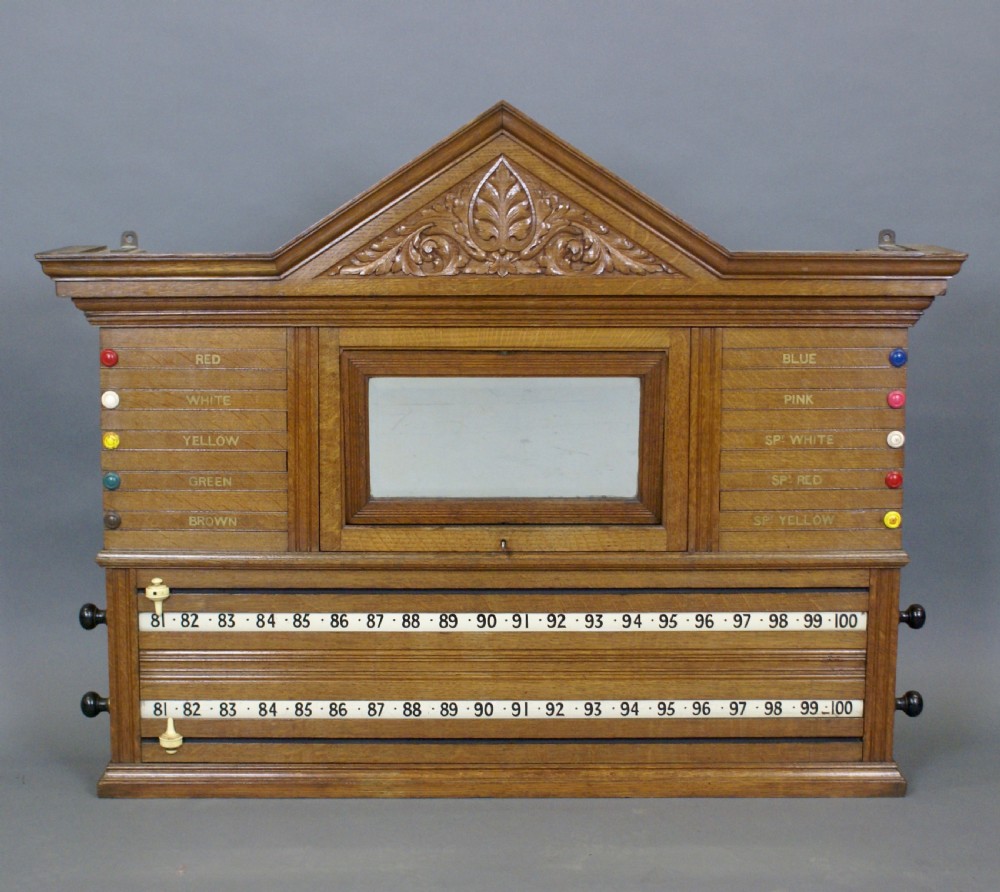 An antique pale oak wall-mounted snooker scoreboard featuring a carved pediment, sliding colour markers, central slate panel, and numbered rolling dials. View II