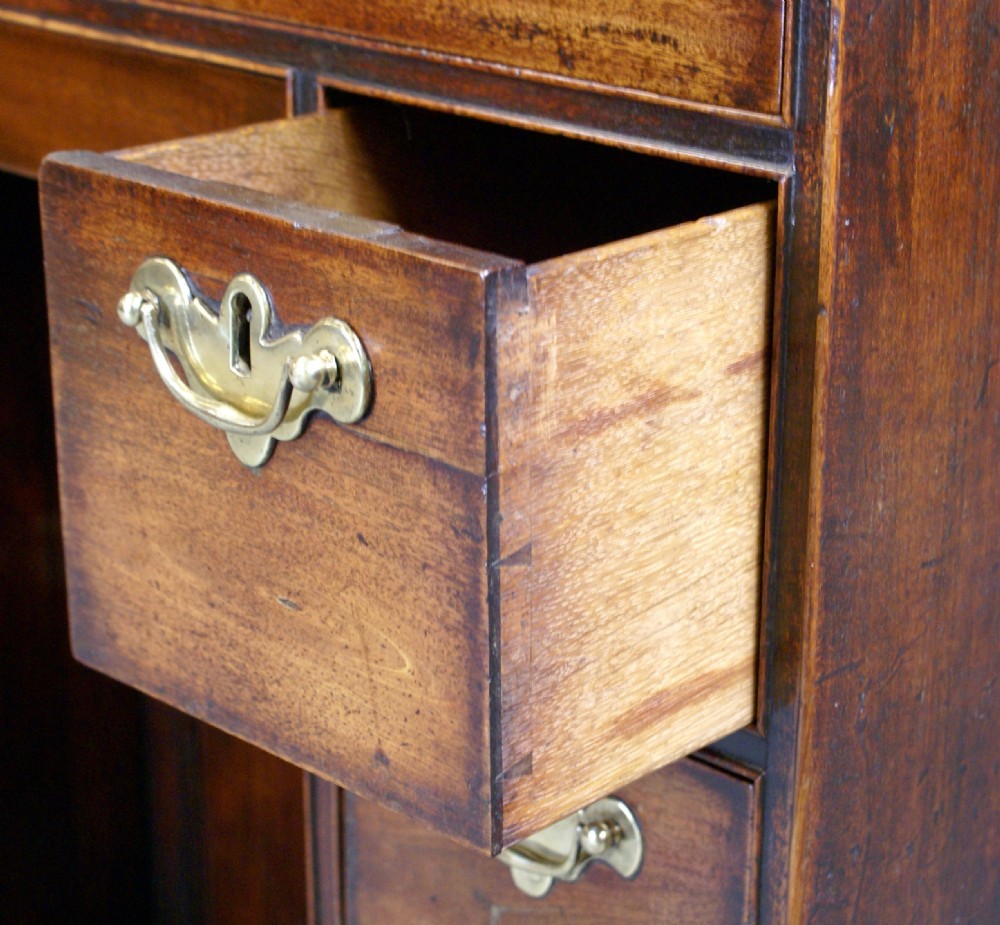 A small George II mahogany kneehole desk with a central recessed cupboard, seven drawers, shaped bracket feet, and brass swing handles. View V