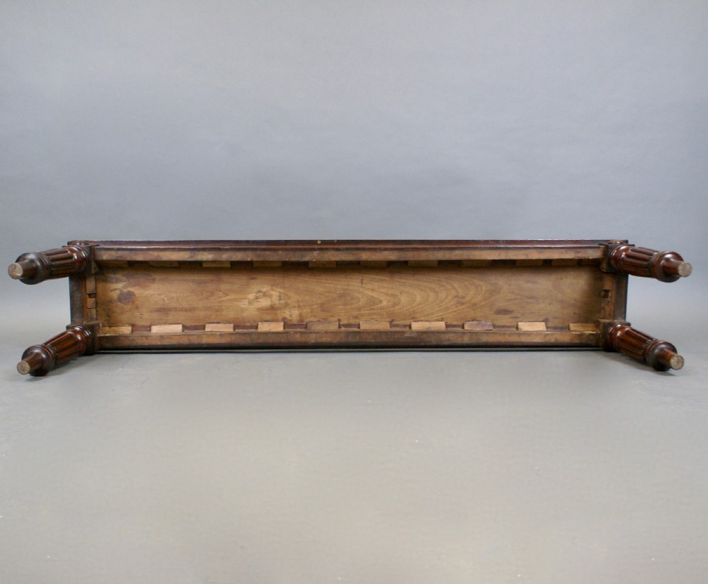 An antique wooden window seat with fluted turned legs and scroll ends on a neutral background. View IX
