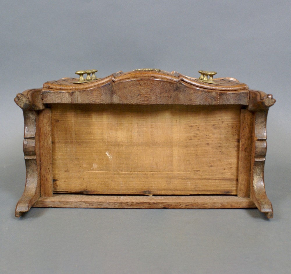 A 19th-century French miniature oak commode featuring a serpentine front, three moulded drawers with brass hardware, and short cabriole legs. View VI