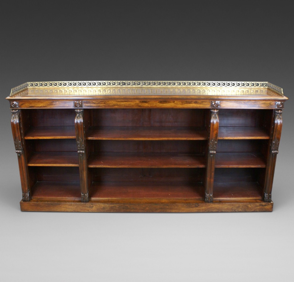 A low Regency rosewood open bookcase featuring three bay shelf sections, carved corbels, and a pierced brass top gallery. View II