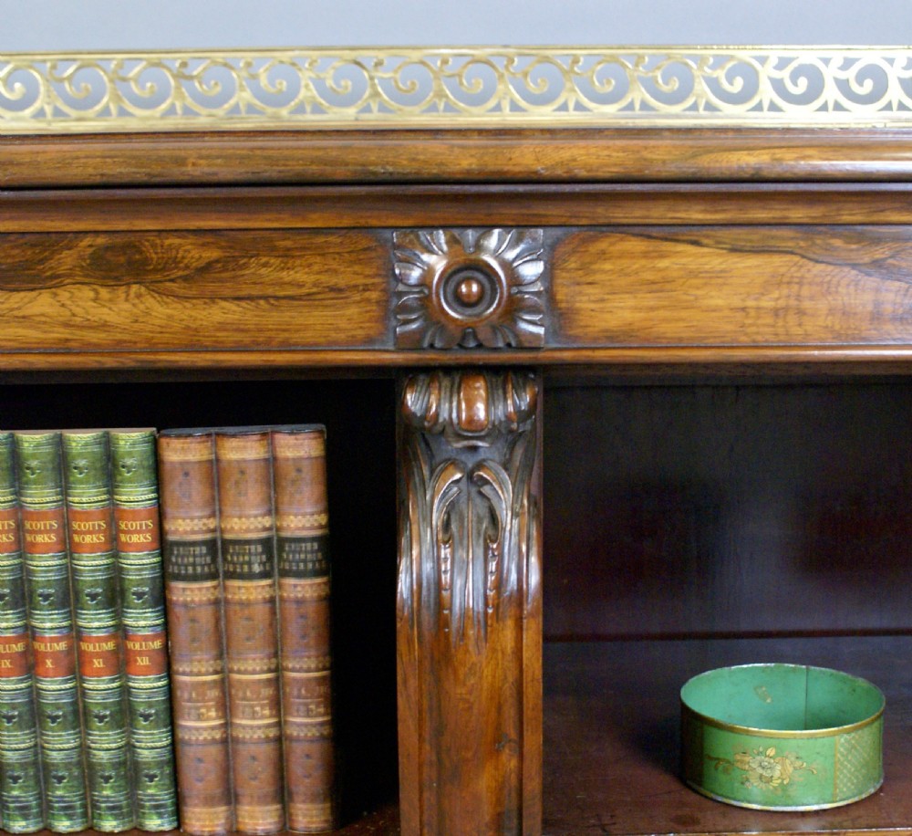 A low Regency rosewood open bookcase featuring three bay shelf sections, carved corbels, and a pierced brass top gallery. View III
