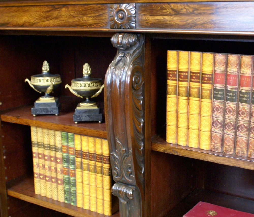 A low Regency rosewood open bookcase featuring three bay shelf sections, carved corbels, and a pierced brass top gallery. View VI