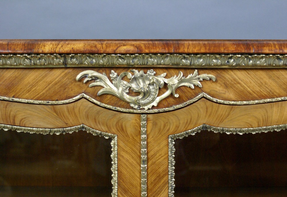 An antique walnut side cabinet featuring central glazed double doors flanked by open curved side shelves and gilt-bronze mounts. View III