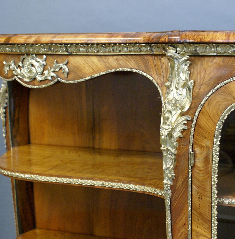 An antique walnut side cabinet featuring central glazed double doors flanked by open curved side shelves and gilt-bronze mounts. View V