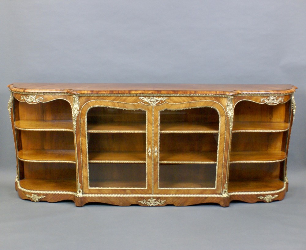 An antique walnut side cabinet featuring central glazed double doors flanked by open curved side shelves and gilt-bronze mounts. View VI