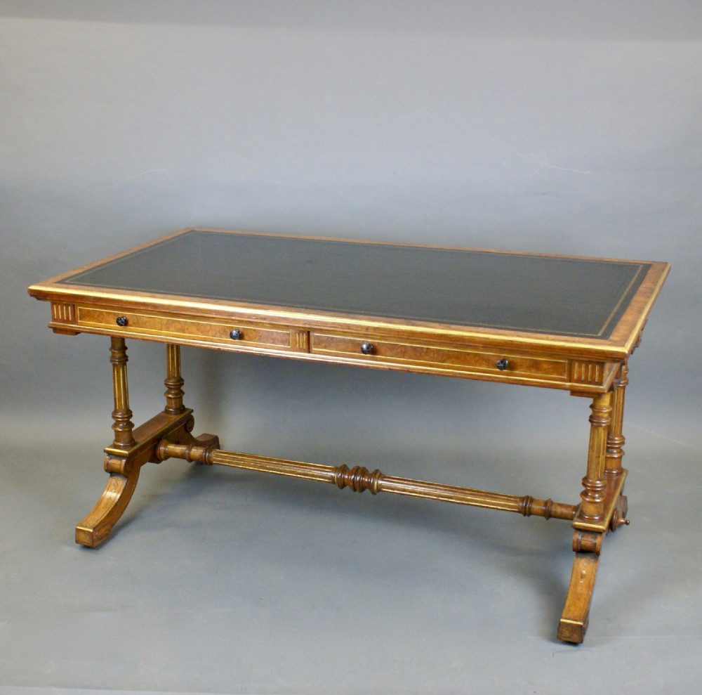 A Victorian burr walnut library writing table featuring a dark green leather inset surface, frieze drawers, turned support legs, and a central stretcher. View III