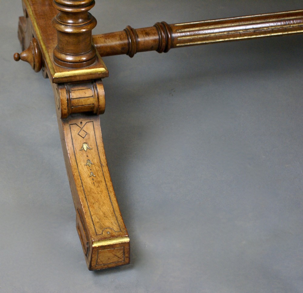 A Victorian burr walnut library writing table featuring a dark green leather inset surface, frieze drawers, turned support legs, and a central stretcher. View VI