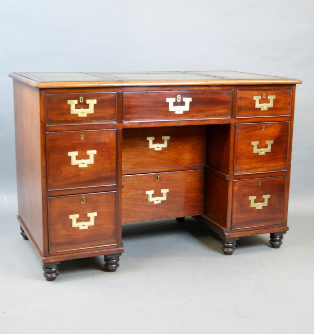 Mid-19th century mahogany military pedestal desk featuring brass flush handles, multiple drawers, and a green leather insert with a raised central writing slope. View V