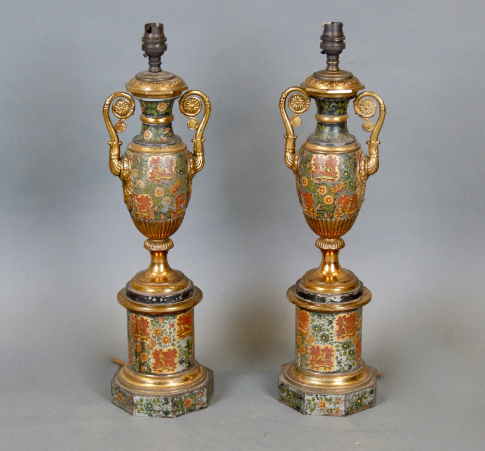 A pair of French classical urn-shaped toleware table lamps featuring hand-painted floral decoration, gilded scroll handles, octagonal pedestals, and pleated cream shades. View II