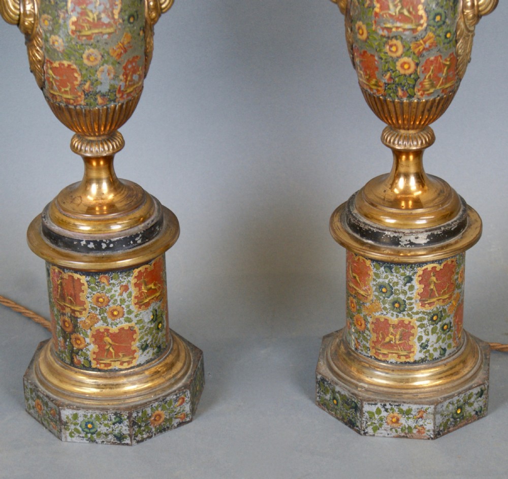 A pair of French classical urn-shaped toleware table lamps featuring hand-painted floral decoration, gilded scroll handles, octagonal pedestals, and pleated cream shades. View V