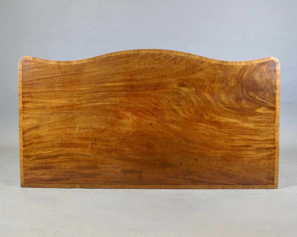 A late 18th-century mahogany serpentine sideboard featuring inlaid fan motifs, three drawers, an arched central apron, and four tapered square legs with spade feet. View III
