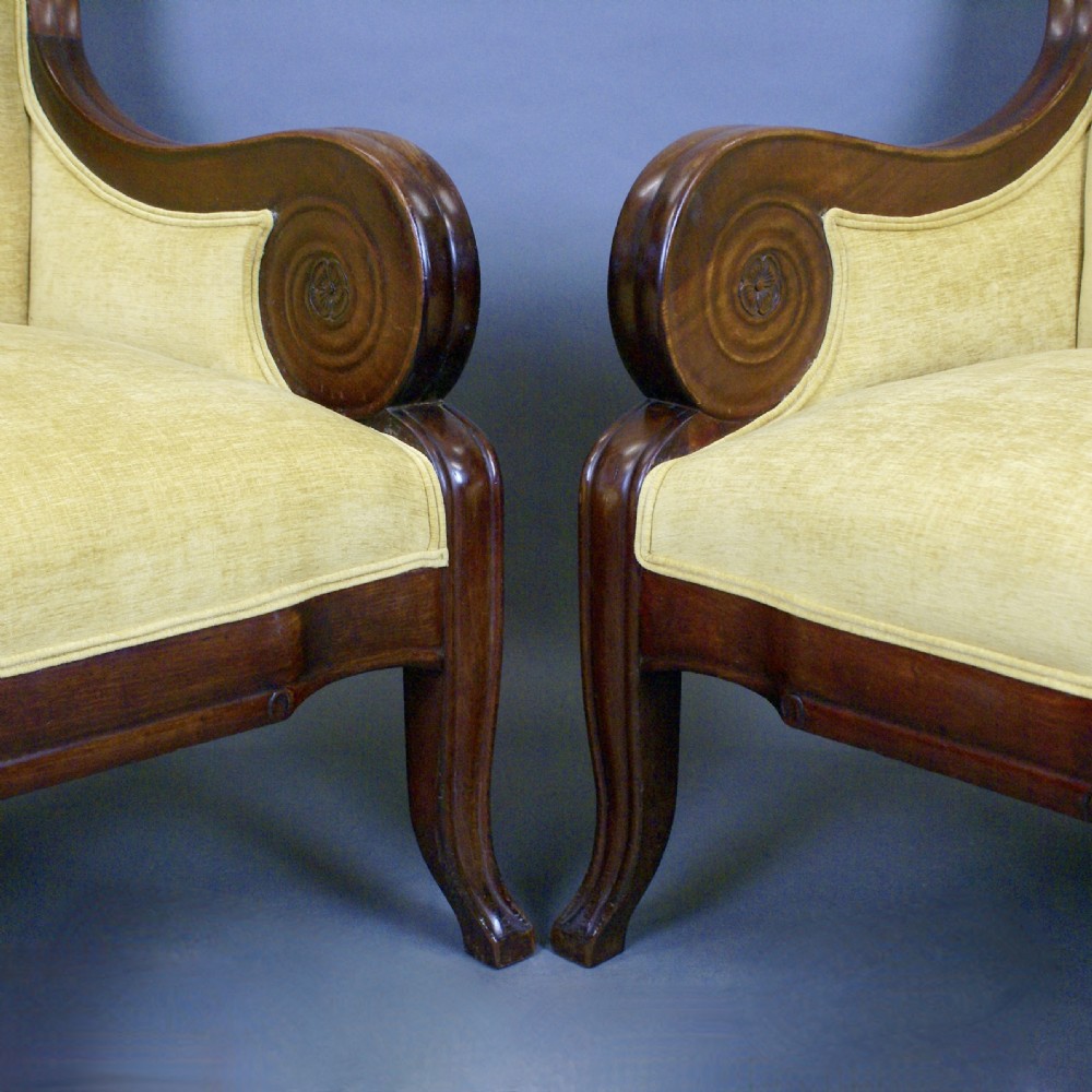 A pair of antique mahogany library armchairs featuring bold scroll arms and yellow fabric upholstery. View V