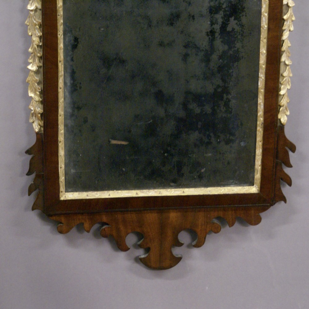 An 18th-century rectangular mahogany wall mirror featuring carved parcel-gilt mouldings, side floral garlands, a scrolled fretwork apron, and a leaf finial cresting. View III