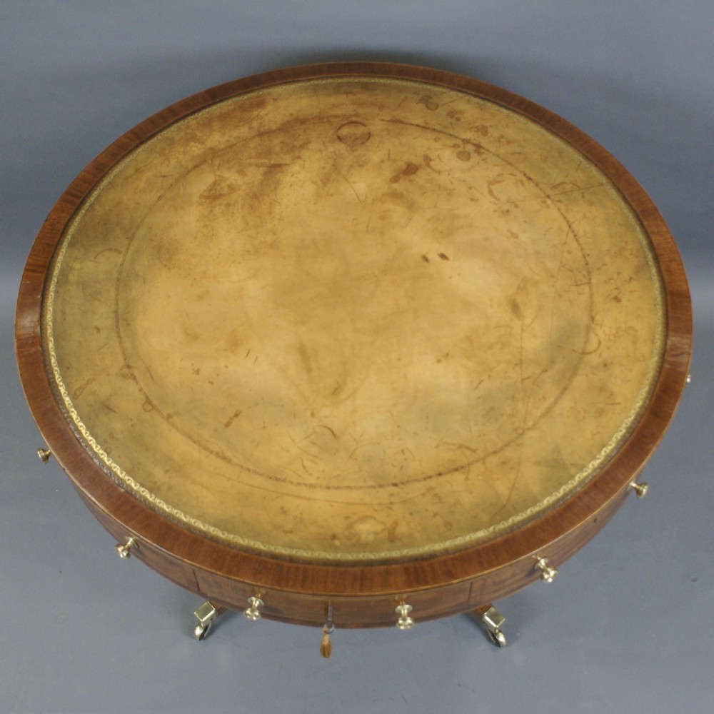 A circular Georgian mahogany drum table with an inset leather top, perimeter frieze drawers with brass knobs, and a turned pedestal on four splayed legs with brass castors. View III