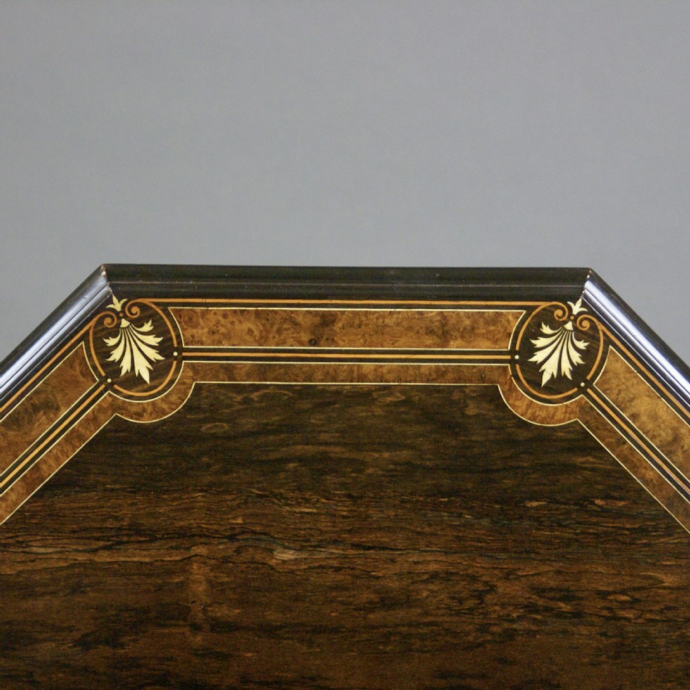 An octagonal dark rosewood occasional table featuring foliate marquetry inlays around the border, turned supports, a cross-stretcher, and splayed legs with brass castors. View VII