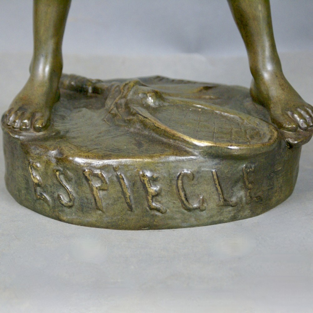 A patinated bronze figure depicting a standing young boy holding a small bird on a naturalistic cast base. View V