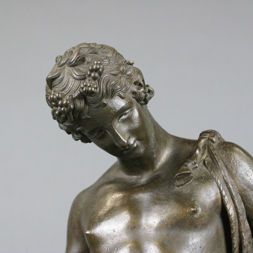 A patinated dark bronze classical figure of a youthful male deity standing on a circular moulded base. View V