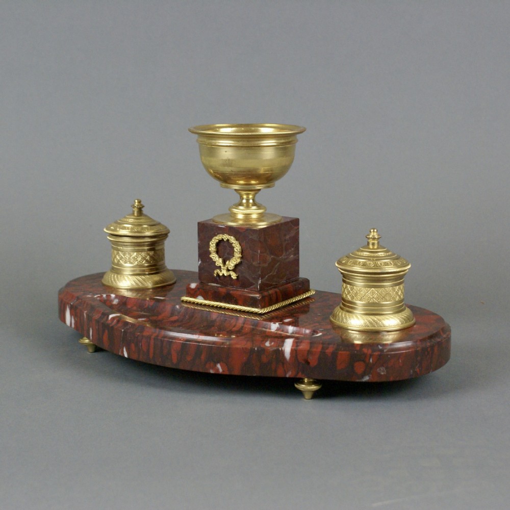 A French Neoclassical red marble inkstand featuring a central gilt urn on a pedestal decorated with a laurel wreath, flanked by two matching gilt inkwells. View II