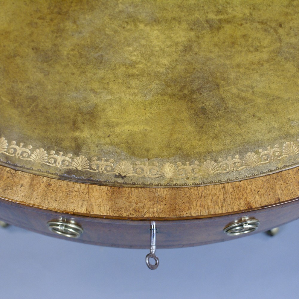 A Regency mahogany drum table featuring a leather-inlaid circular top, drawers with brass ring pulls, and splayed quadripartite legs with brass claw castors. View III
