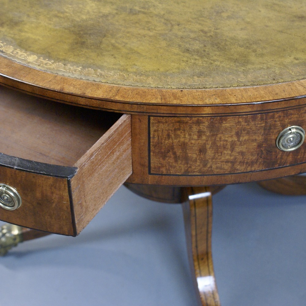 A Regency mahogany drum table featuring a leather-inlaid circular top, drawers with brass ring pulls, and splayed quadripartite legs with brass claw castors. View VI
