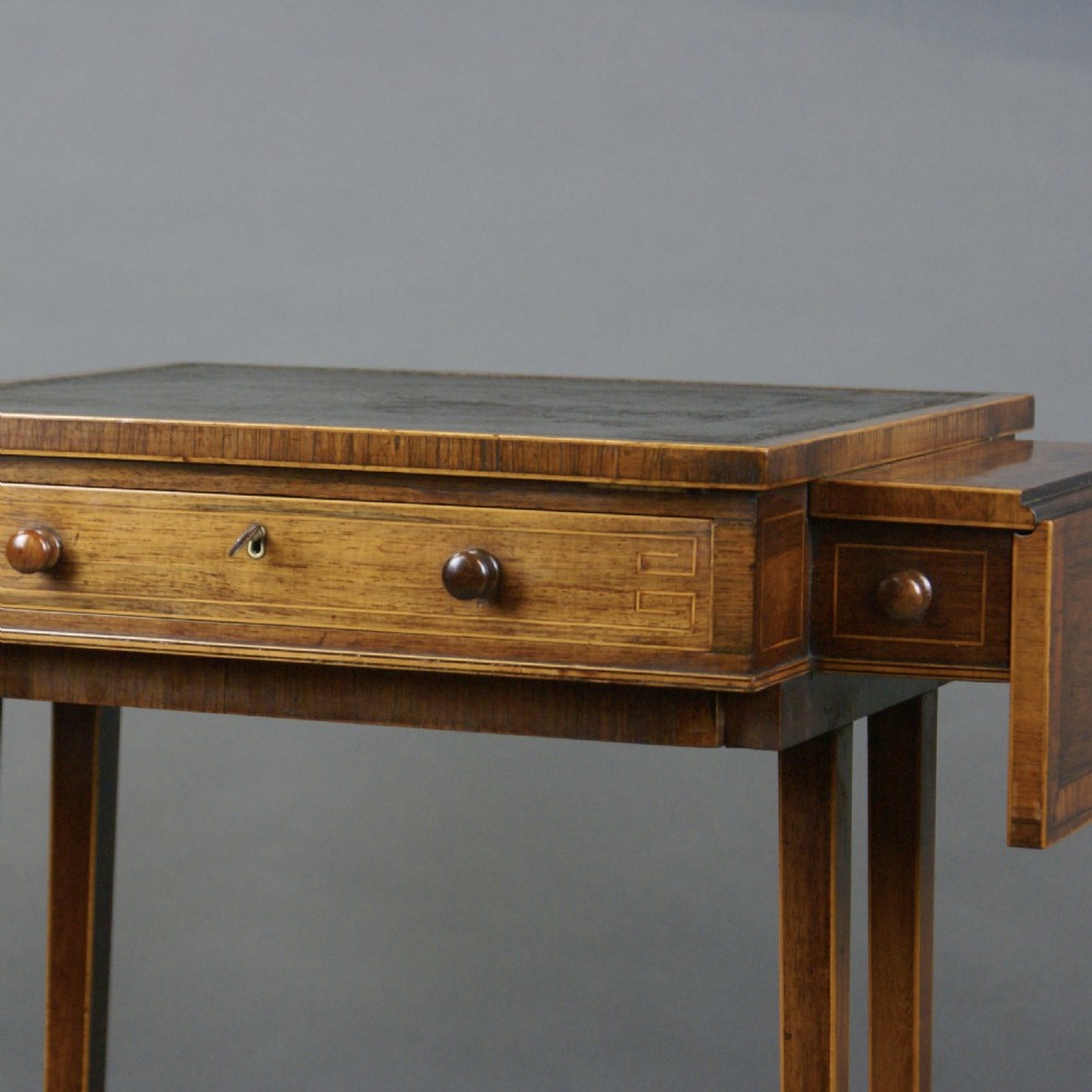 A small Regency rosewood writing table with a dark leather inset top, two drop flaps, a frieze drawer, and slender twin supports on splayed feet. View VI