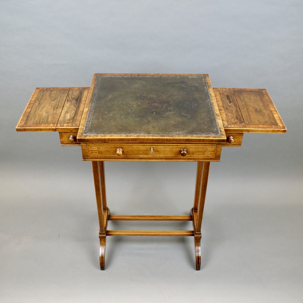 A small Regency rosewood writing table with a dark leather inset top, two drop flaps, a frieze drawer, and slender twin supports on splayed feet. View VII
