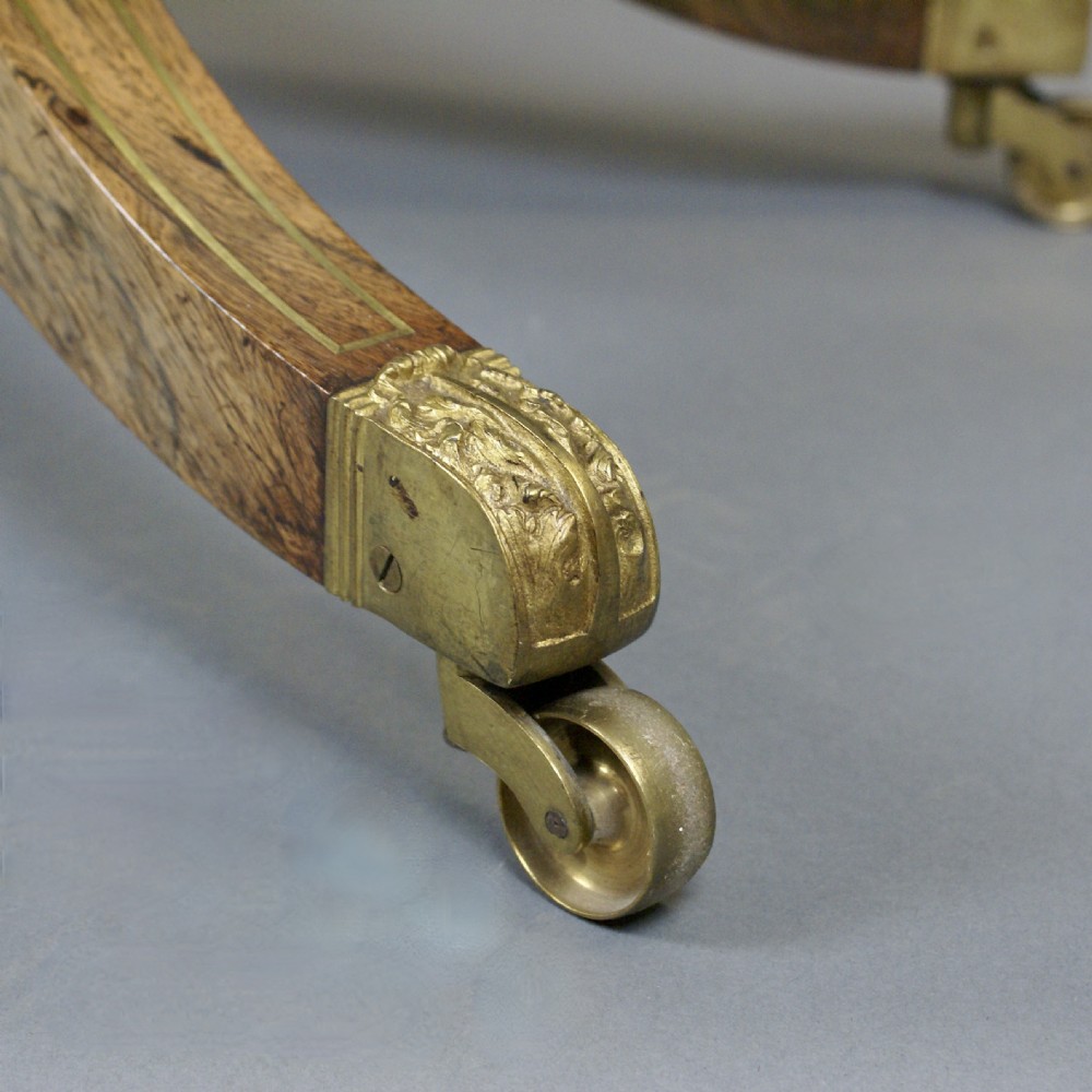 A Regency rosewood fold-over card table featuring brass inlay, a central pedestal stem, and four splayed legs with brass castors. View VI