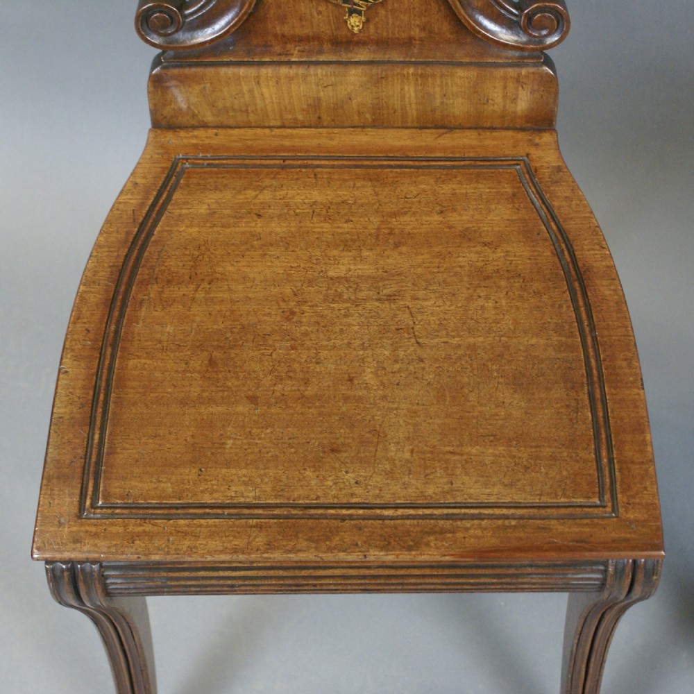 A pair of carved mahogany hall chairs featuring scalloped shell backs with painted crests and reeded front legs. View VI