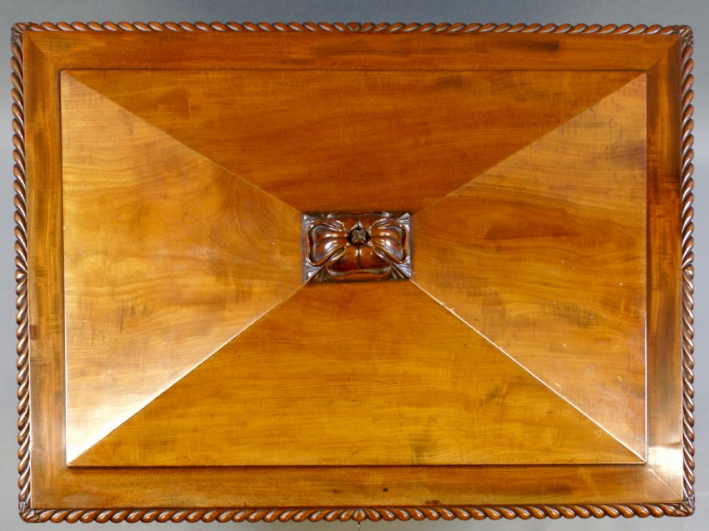 An antique Regency flame mahogany sarcophagus-shaped wine cooler featuring a pyramidal lid with carved finial, gadrooned borders, and scroll feet. View VII