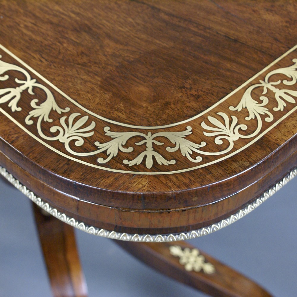 A pair of Regency dark rosewood card tables featuring fold-over rectangular tops decorated with brass floral inlays on curved sweeping legs with brass castors. View III