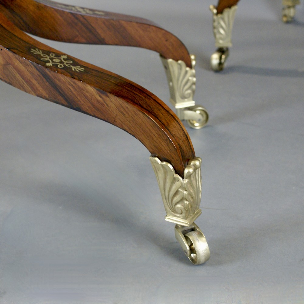 A pair of Regency dark rosewood card tables featuring fold-over rectangular tops decorated with brass floral inlays on curved sweeping legs with brass castors. View VII