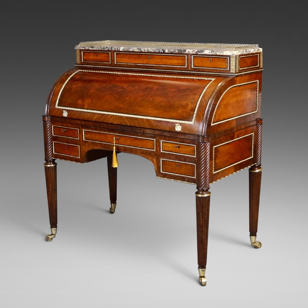 A Regency mahogany cylinder desk featuring a marble top with a brass gallery, brass-inlaid drawers, reeded tapered legs, and brass castors. View III