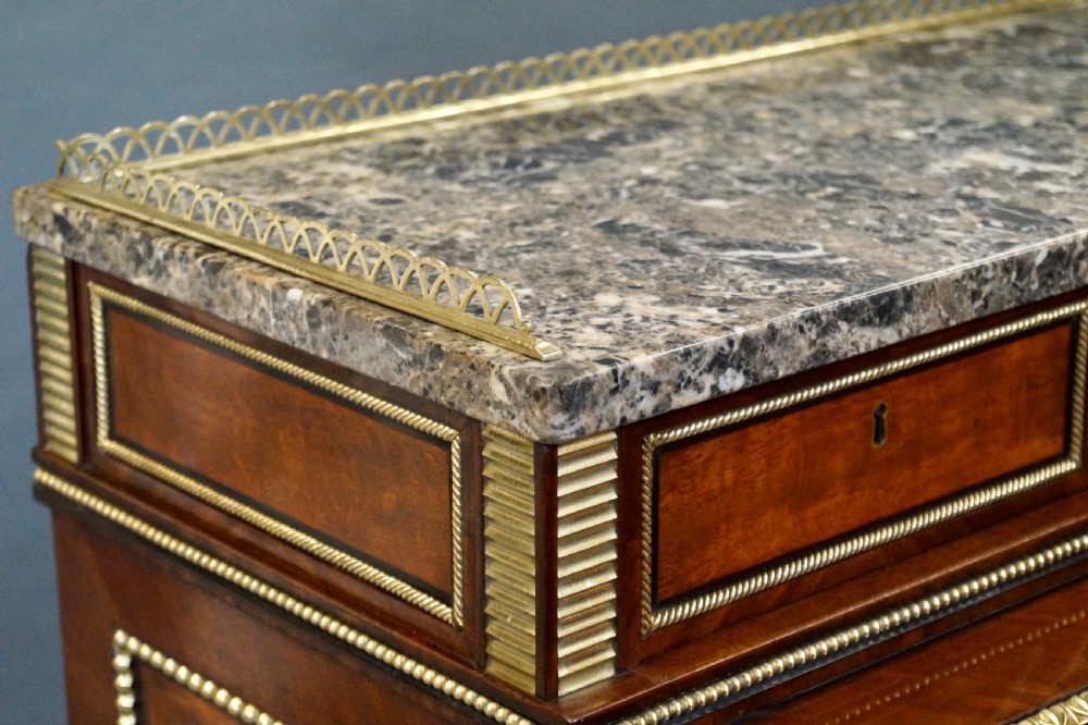 A Regency mahogany cylinder desk featuring a marble top with a brass gallery, brass-inlaid drawers, reeded tapered legs, and brass castors. View VII