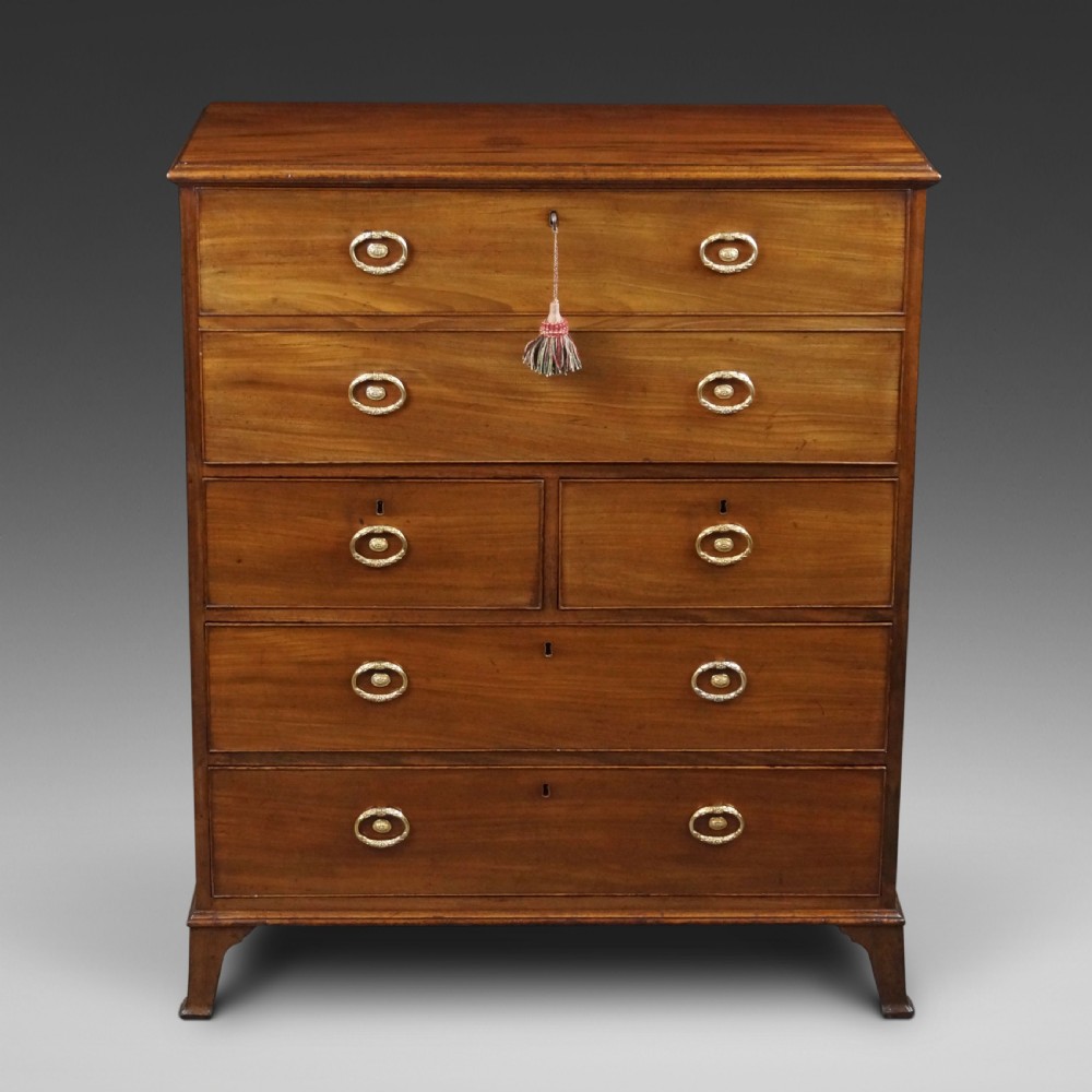 An antique mahogany secretaire chest of drawers featuring brass oval backplate handles, cockbeaded drawer edges, and bracket feet.