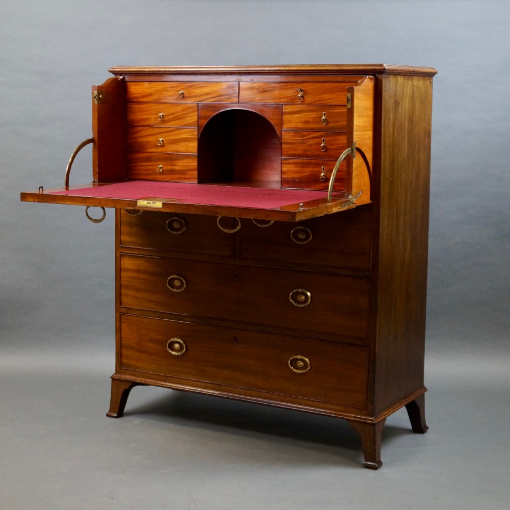 An antique mahogany secretaire chest of drawers featuring brass oval backplate handles, cockbeaded drawer edges, and bracket feet. View II